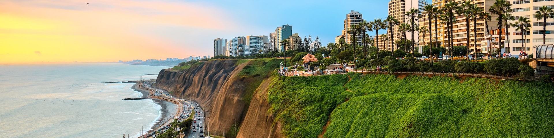 Un paisaje urbano costero con un acantilado escarpado, una playa y una carretera que bordea el acantilado.