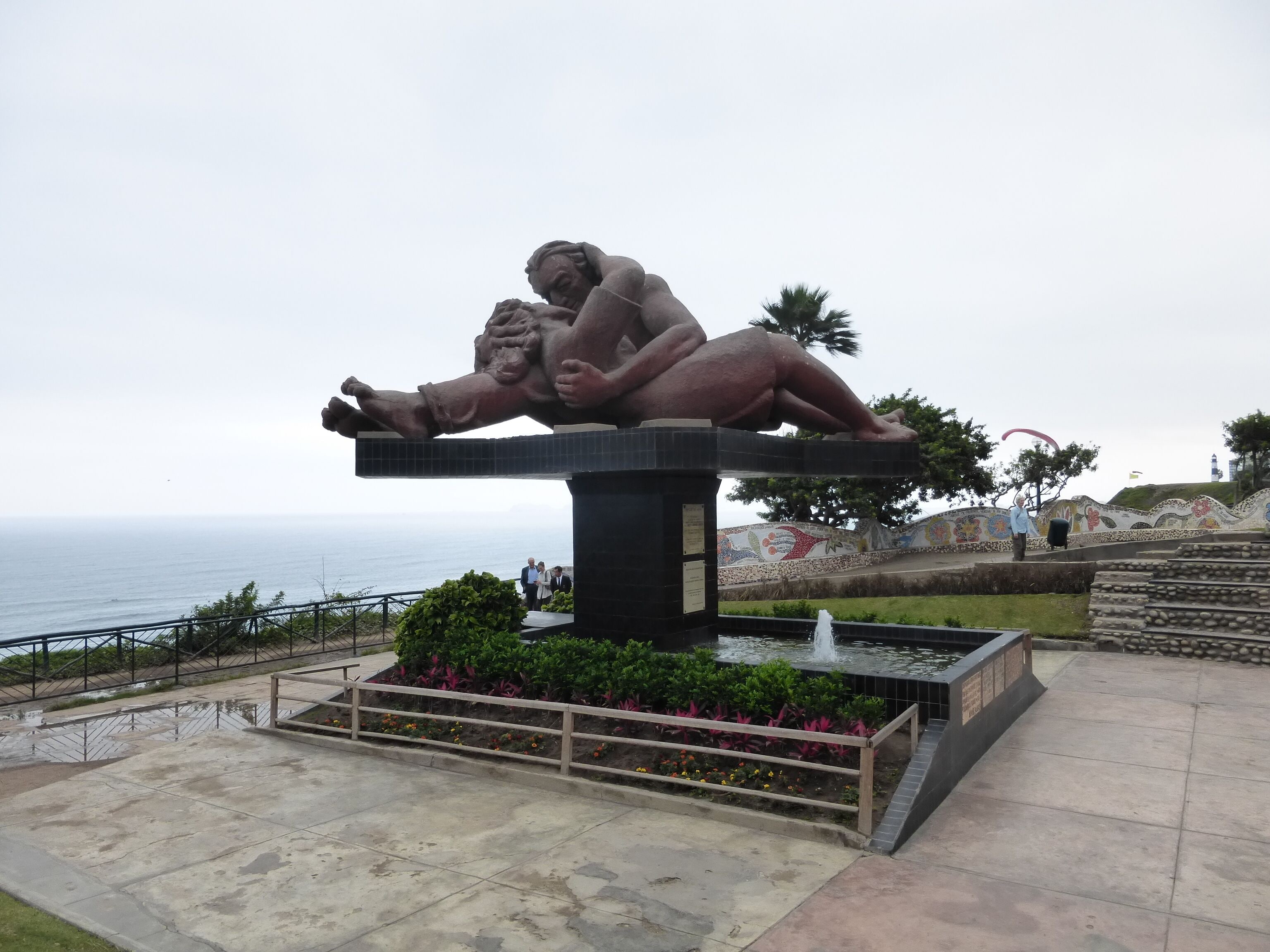 Une grande sculpture en plein air représentant une figure allongée, une fontaine et une vue sur la côte.