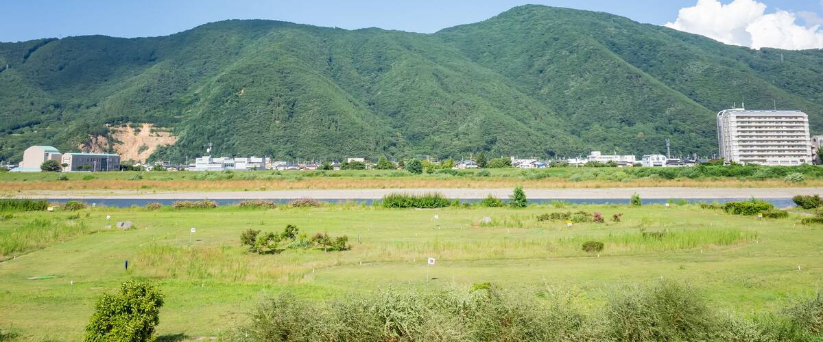 A mountainous landscape with a river in the foreground and a building in the background.
