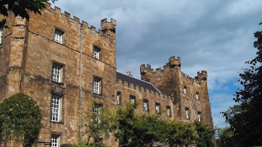 A historic castle with multiple towers and a well-maintained lawn.