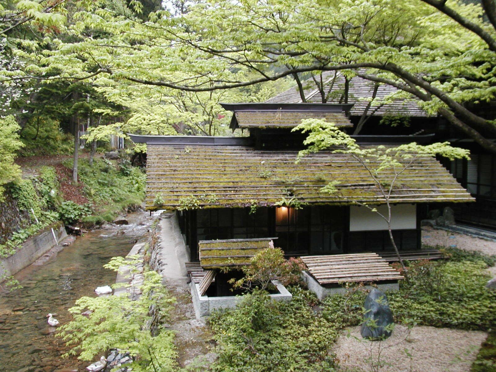 A traditional Japanese house with a koi pond and a stream.