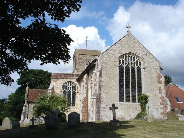 A church with a tall steeple, large arched windows, and a graveyard in front.