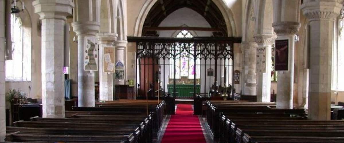 An interior of a church with a red carpet aisle, arched ceilings, and wooden pews.