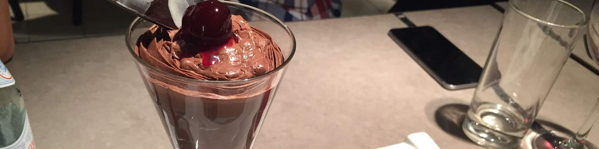 A dessert with a cherry on top, a chocolate piece, and a strawberry on a white plate.