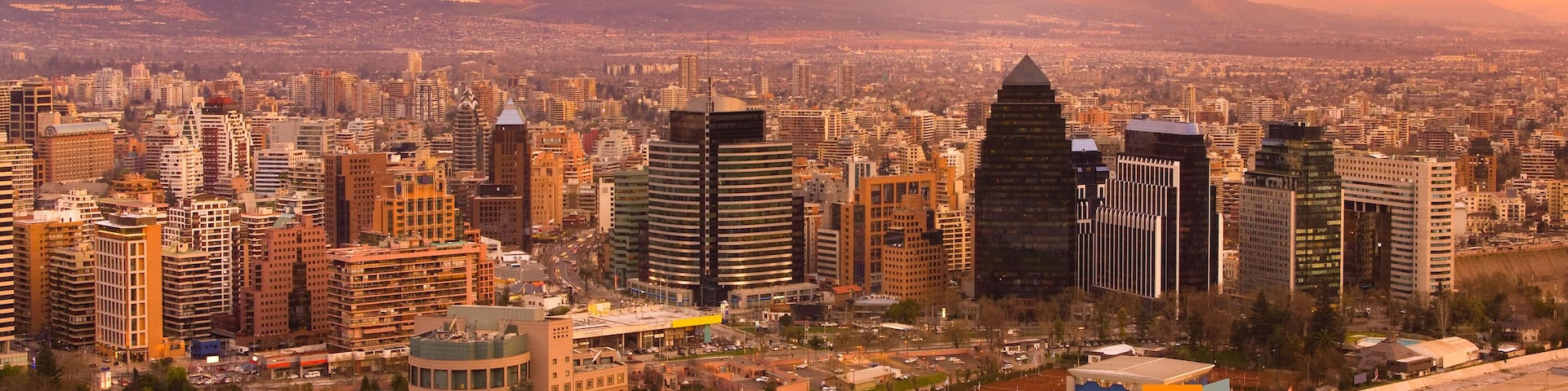 A cityscape with modern buildings, a highway, and mountains in the background.