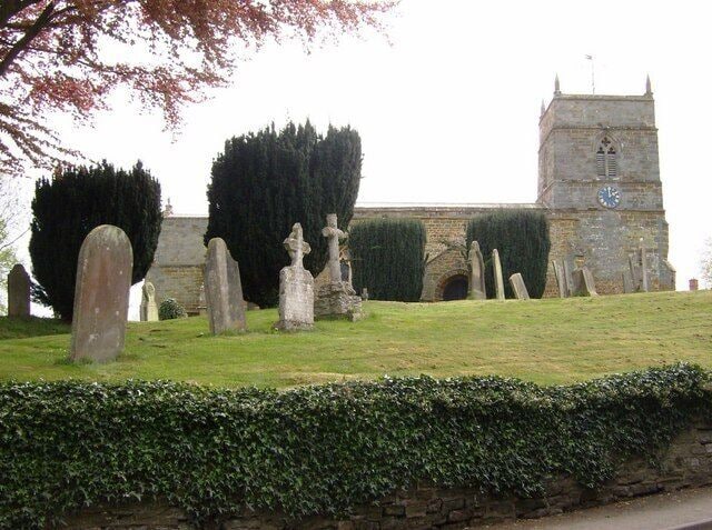 A church with a clock tower and gravestones in the foreground.