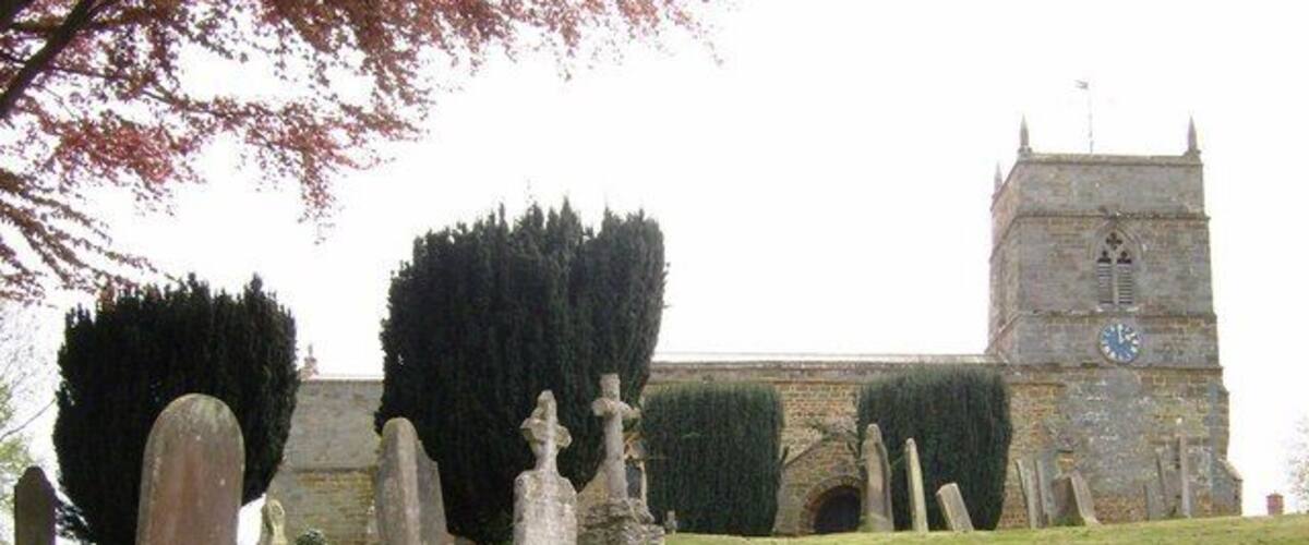 A church with a clock tower and gravestones in the foreground.
