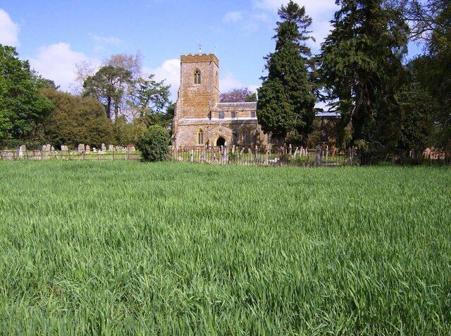 All Saints church, Flore From the south. A footpath carries the Macmillan Way and Nene Way long distance paths out of Flore across this arable field, with this view back to the church.