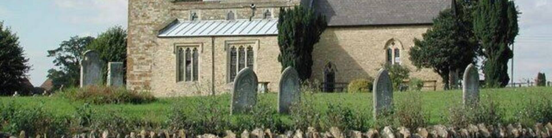 A stone church with a bell tower and a graveyard.