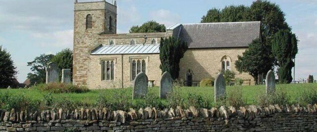 A stone church with a bell tower and a graveyard.
