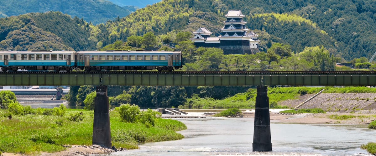 A limited express train on the Tokushima Line crossing the iron bridge over the Anabuki River in Ozu, Japan, Aug 2023