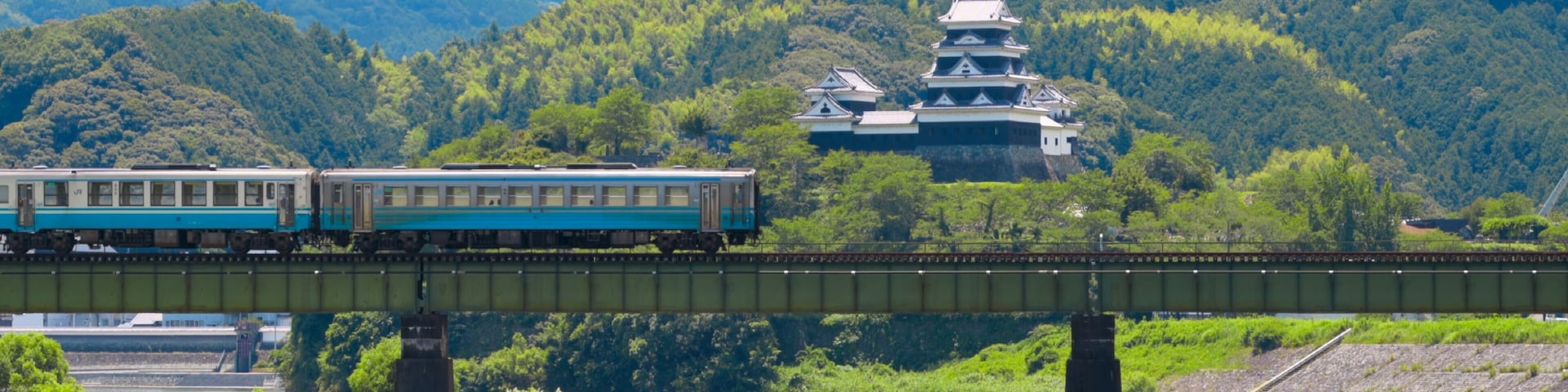 A limited express train on the Tokushima Line crossing the iron bridge over the Anabuki River in Ozu, Japan, Aug 2023