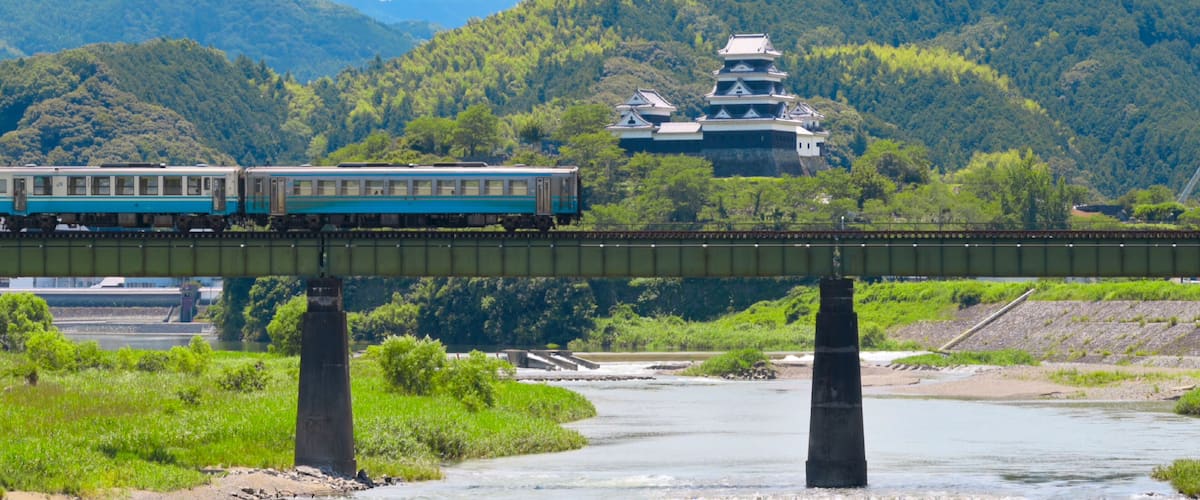 A limited express train on the Tokushima Line crossing the iron bridge over the Anabuki River in Ozu, Japan, Aug 2023