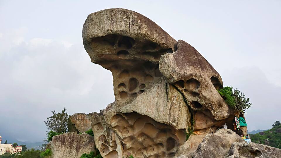 A large rock formation with multiple cavities and a small shrine.