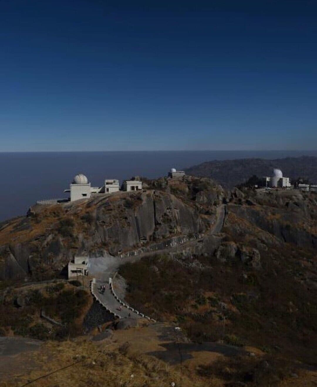 Mount Abu is the only hill station in the deserts of Rajasthan. It is nestled amongst the green forests on the state's highest mountain at the Southwestern end of Aravallis, close to the Gujarat border.
Mt Abu sits towards the Southwestern end of the plateau-like mountain which stretches about 19 km from end to end and 6 km from East to West and is surrounded by the 289 km2 Mt Abu Wildlife Sanctuary. Situated at an elevation of 1,220 meters (4000 ft) in the Aravalli ranges is the only hill station of Rajasthan, Mount Abu. It has evolved over the years into the state’s favourite getaway for beating the sweltering desert heat. Covered with lush greenery, scenic lakes, hilltop temples, undisturbed trekking trails, serenity and abundant heritage, this hill station offers a relaxing atmosphere.