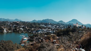 Um lago rodeado por montanhas, uma cidade com edifícios e um farol.