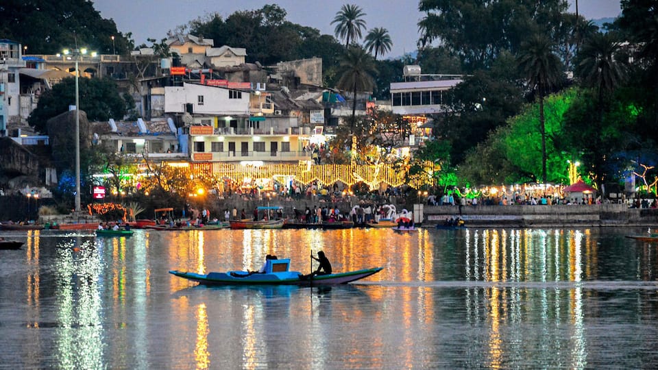 A river with boats, a crowd on the shore, and buildings in the background.