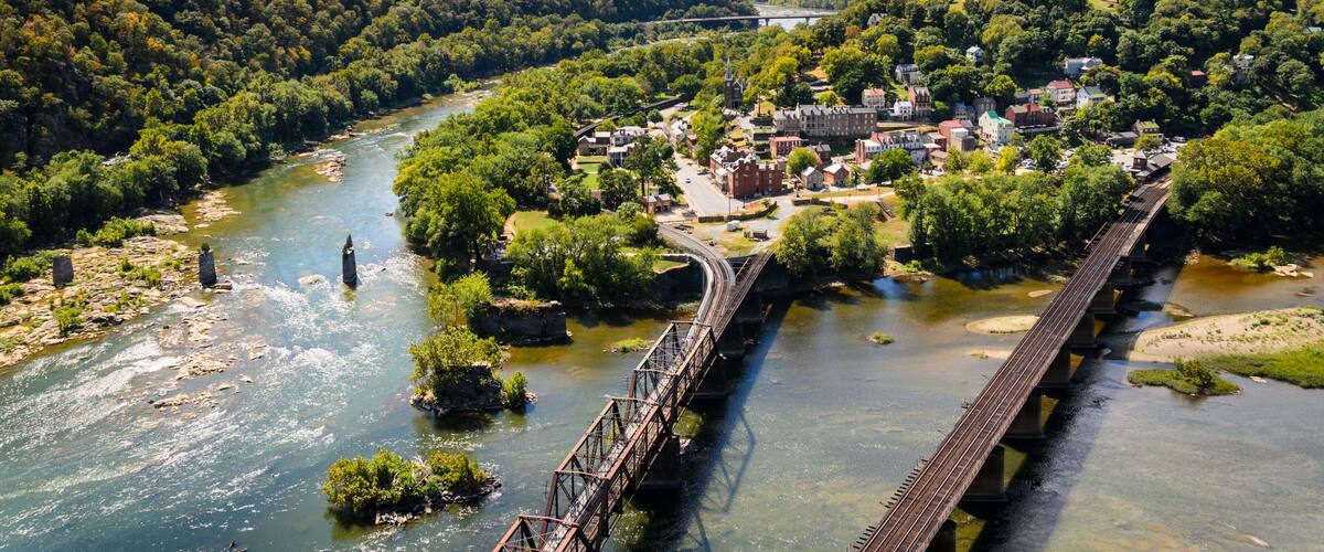 A river flowing through a town with a bridge and a hill in the background.