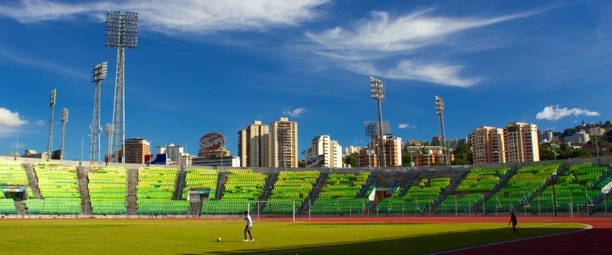 A stadium with green seats, a running track, and tall floodlights.