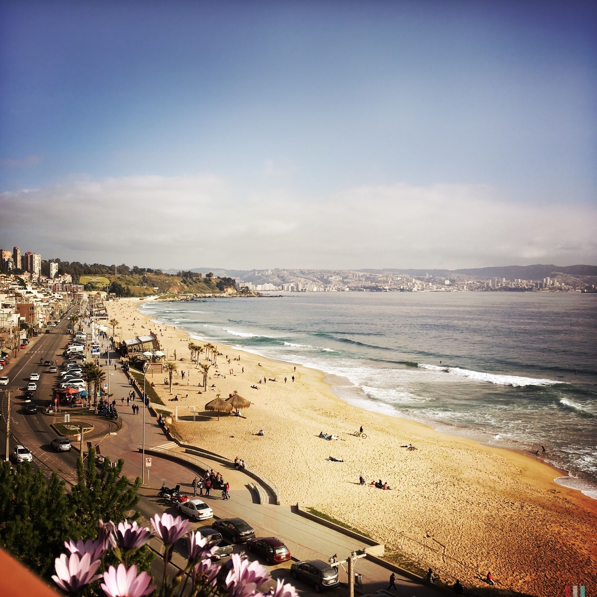A coastal cityscape with a beach, cars, and buildings.