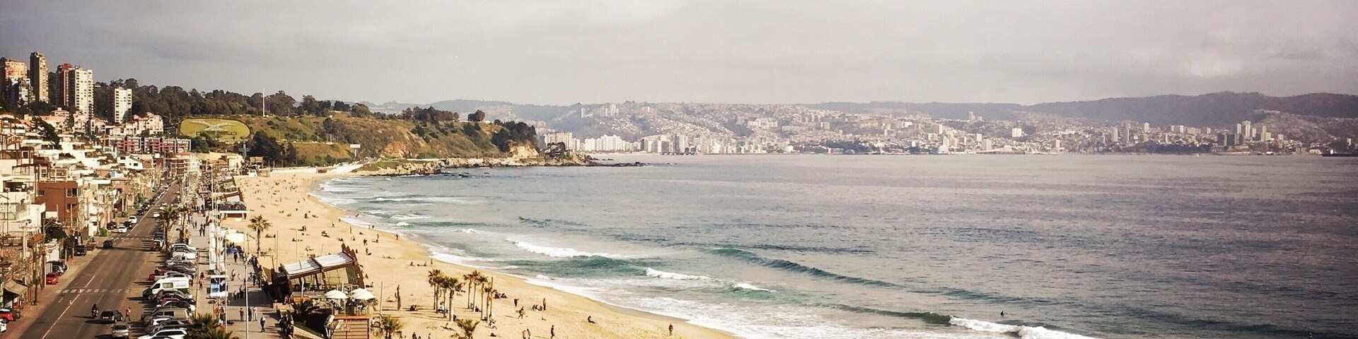 Un paisaje urbano costero con playa, coches y edificios.