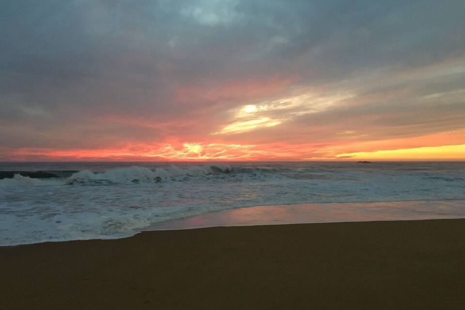 Uma praia com ondas e um pôr do sol.