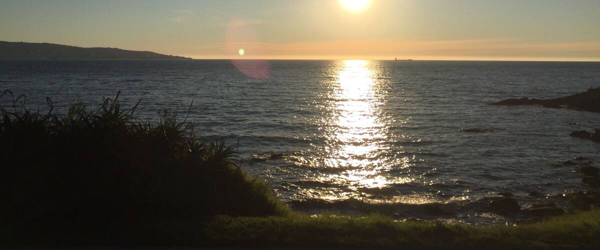 A sunset over a calm sea with a distant landmass.