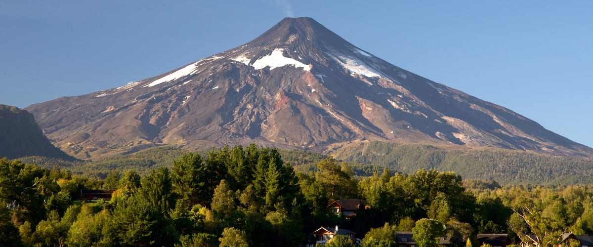 A snow-capped mountain with a forested valley below.
