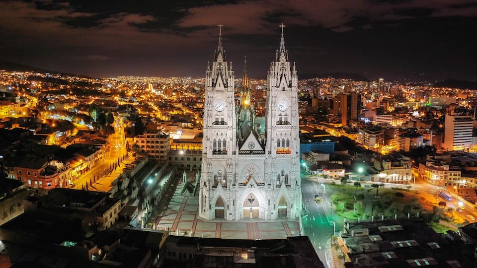 A cathedral with twin spires, a cityscape at night, and illuminated streets.
