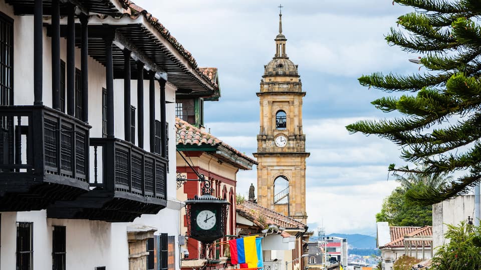 A historic town with a prominent clock tower, traditional architecture, and colorful flags.