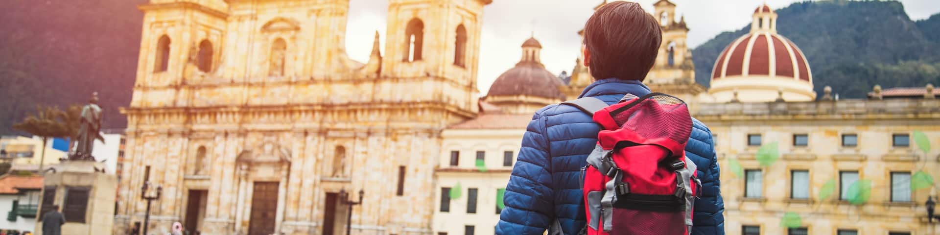 Young man traveling in Bogota, Colombia. Plaza de Bolívar, La Candelaria neighborhood. Taking some photos with the Catedral Primada.