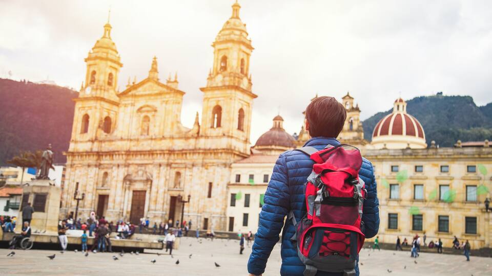 Young man traveling in Bogota, Colombia. Plaza de Bolívar, La Candelaria neighborhood. Taking some photos with the Catedral Primada.