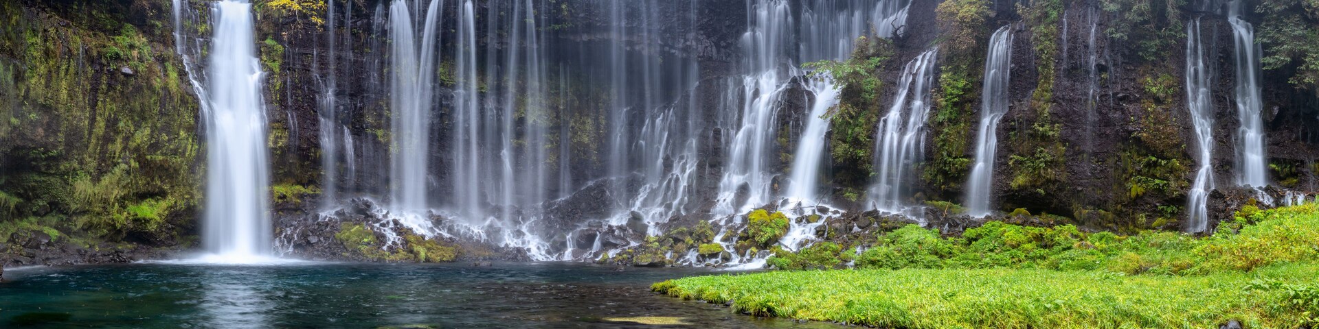 Una cascada en varios niveles que se precipita en una poza cristalina rodeada de exuberante vegetación.