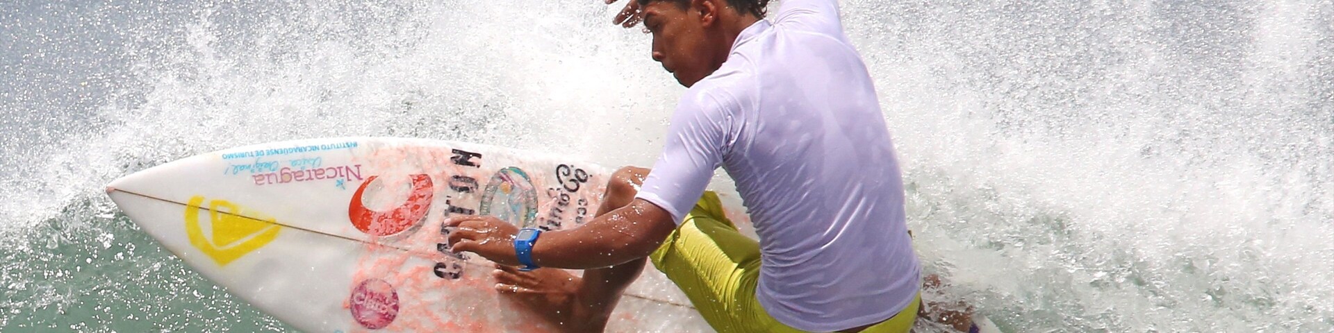 Un surfista cabalgando una ola en una tabla de surf con varios logotipos y texto.