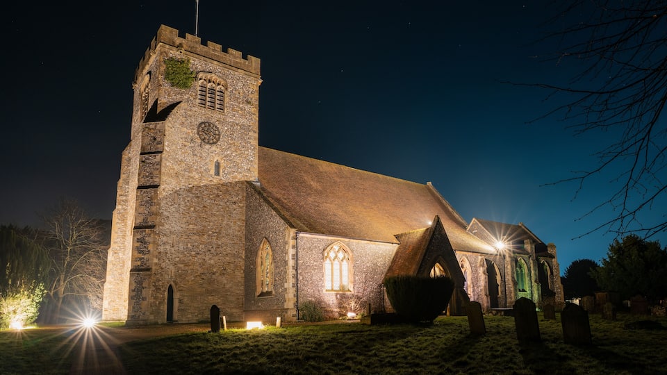 A historic church with a tall tower and arched windows at night.