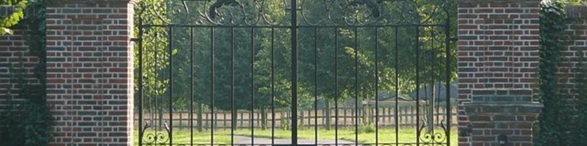 Una entrada protegida por un muro de ladrillo y una reja metálica.