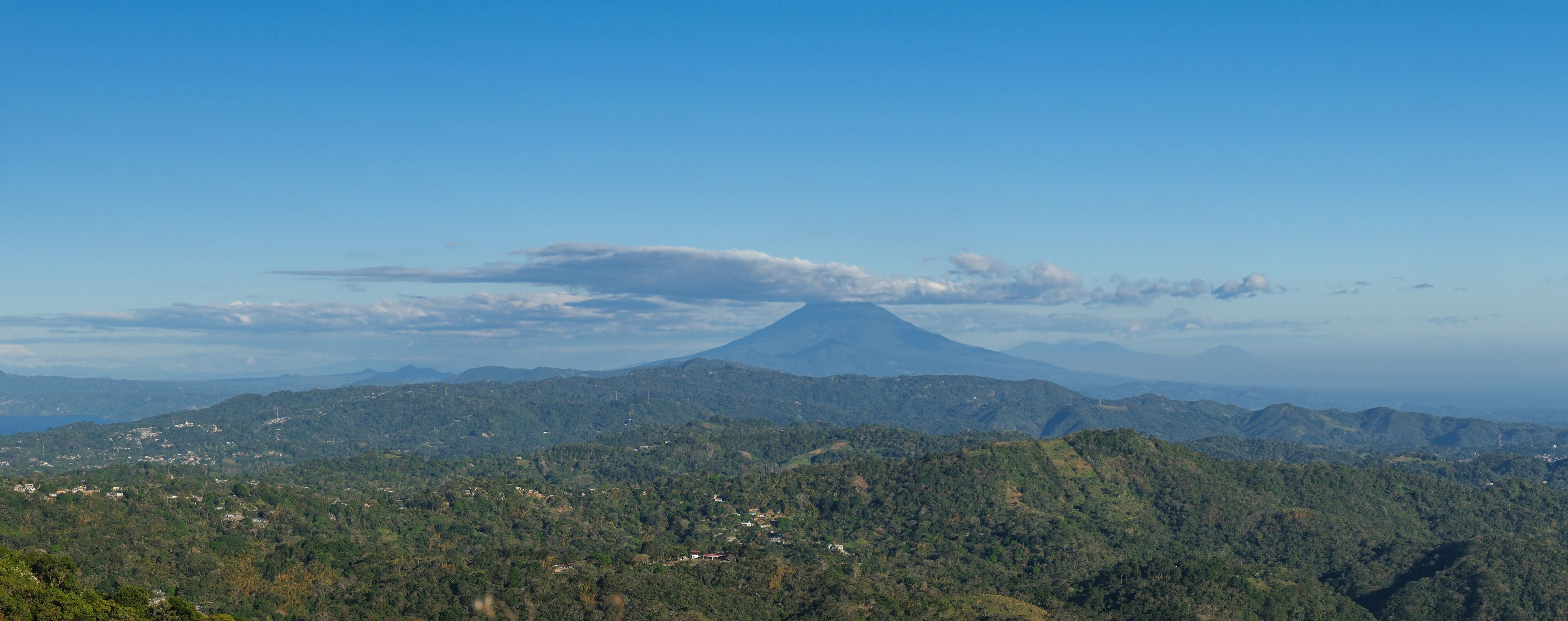 Panoramic view of a cloud capped San Miguel volcano surrounded by lush green hills and mountains. Puerto Del Diablo lookout, El Salvador.