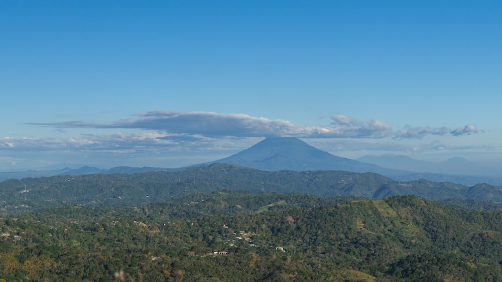 Panoramic view of a cloud capped San Miguel volcano surrounded by lush green hills and mountains. Puerto Del Diablo lookout, El Salvador.