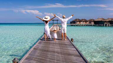 A wooden pier extending into turquoise water with overwater bungalows in the background.