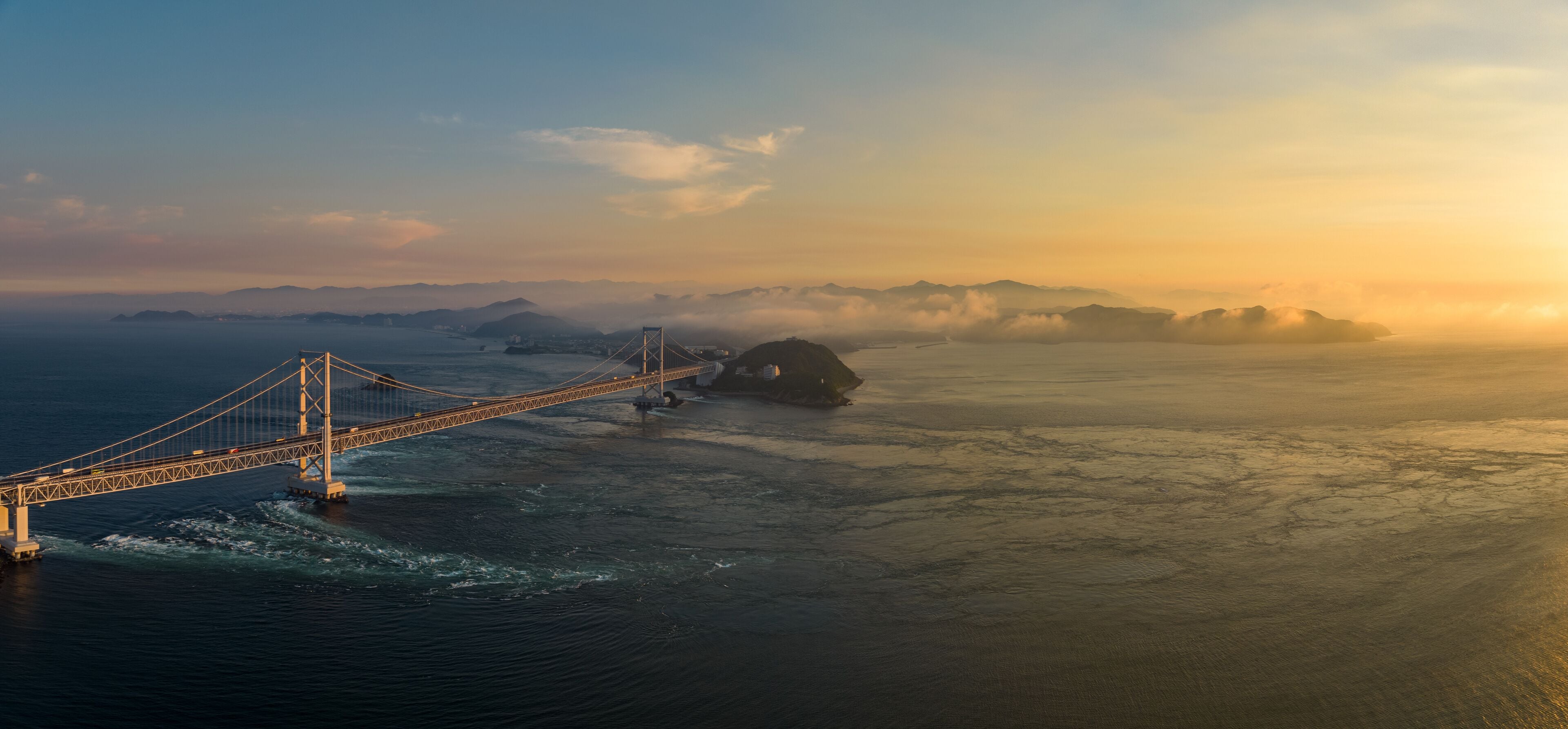 Panoramic aerial view of Naruto Bridge and whirlpools at sunset