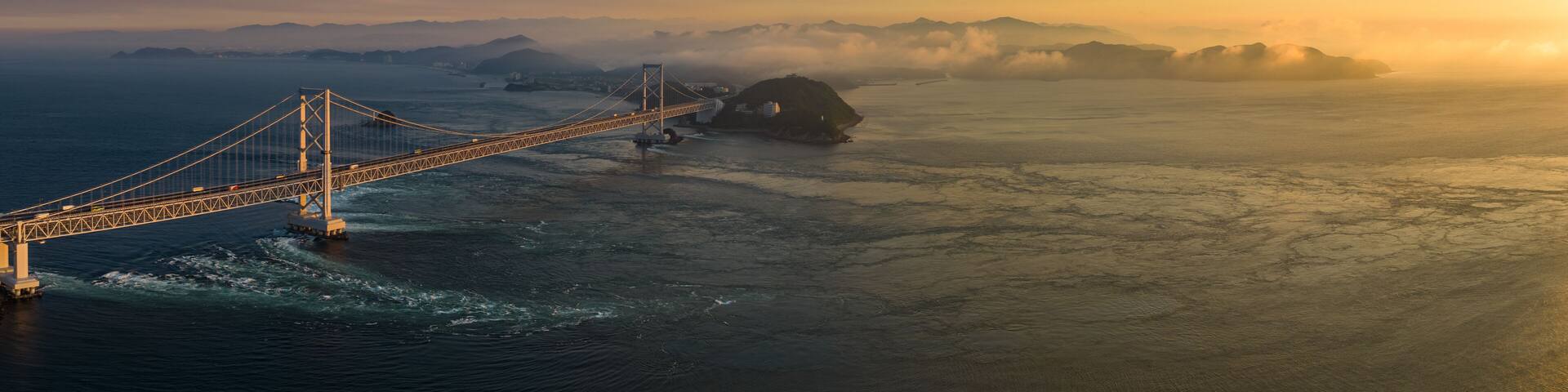 Panoramic aerial view of Naruto Bridge and whirlpools at sunset