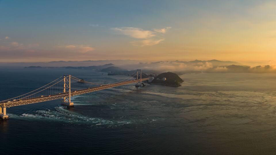 A suspension bridge over a body of water with islands in the distance.