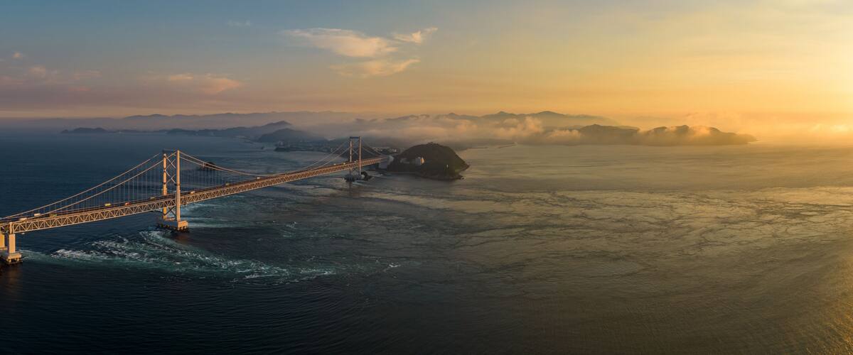 Panoramic aerial view of Naruto Bridge and whirlpools at sunset