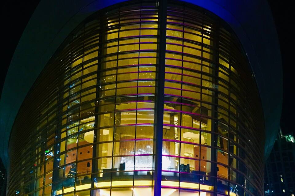 A modern building with a curved glass facade and illuminated interior.