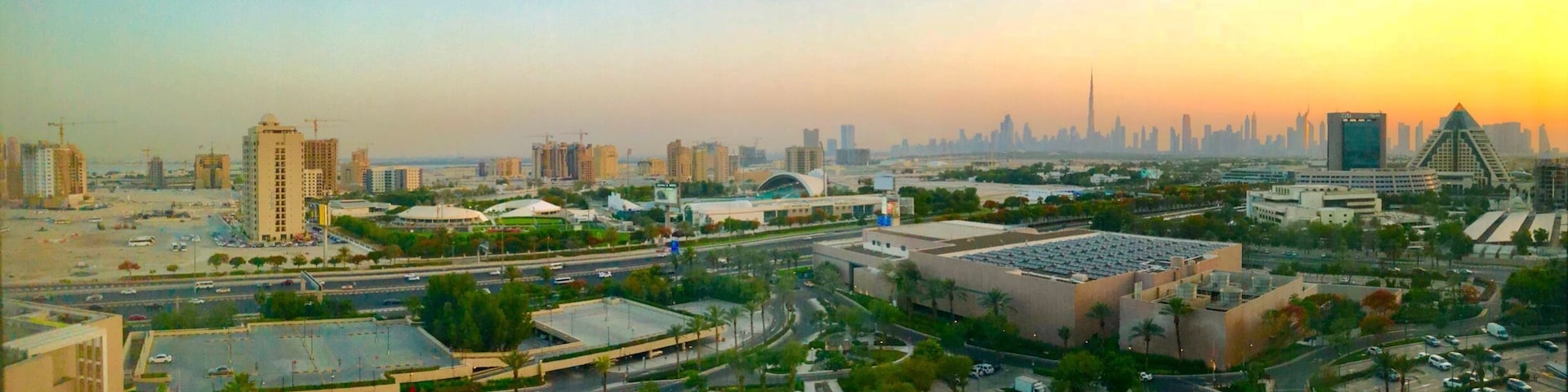 Paisagem urbana com um arranha-céu imponente, uma rotatória e um edifício grande com uma estrutura de telhado peculiar.
