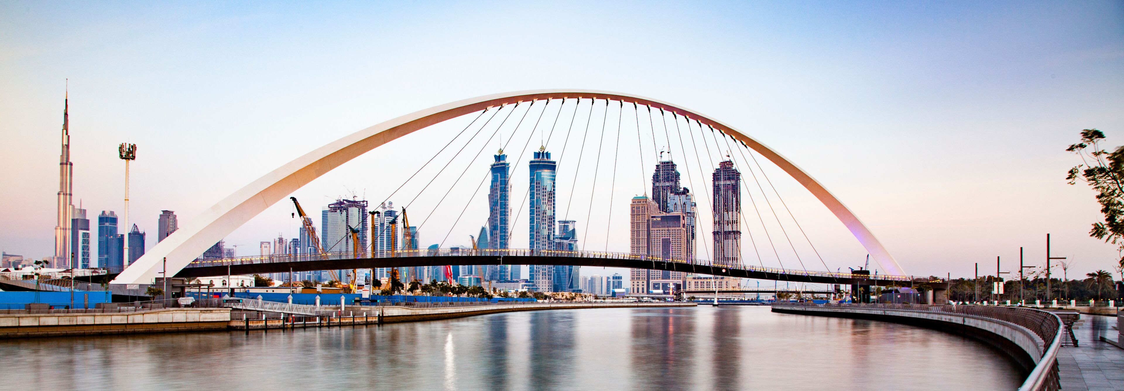 colorful sunset over Dubai Downtown skyscrapers and the newly built Tolerance bridge as viewed from the Dubai water canal