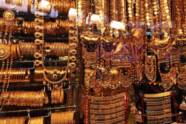 A display of various gold jewelry items, including bangles, necklaces, and earrings, in a store.