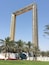A tall, ornate archway with intricate patterns, surrounded by palm trees and a well-maintained lawn.