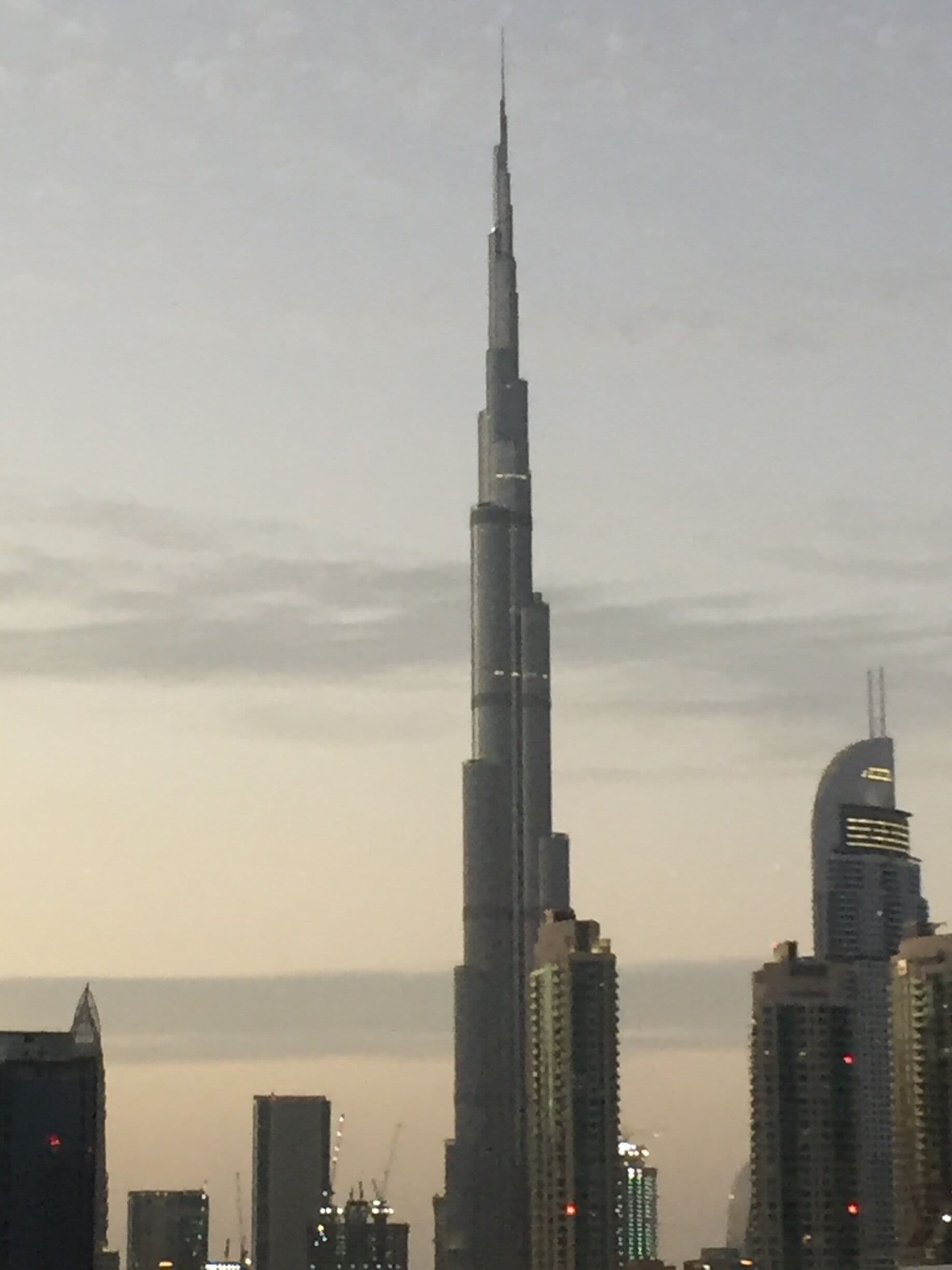 A cityscape with a prominent skyscraper, likely the Burj Khalifa, and other high-rise buildings.