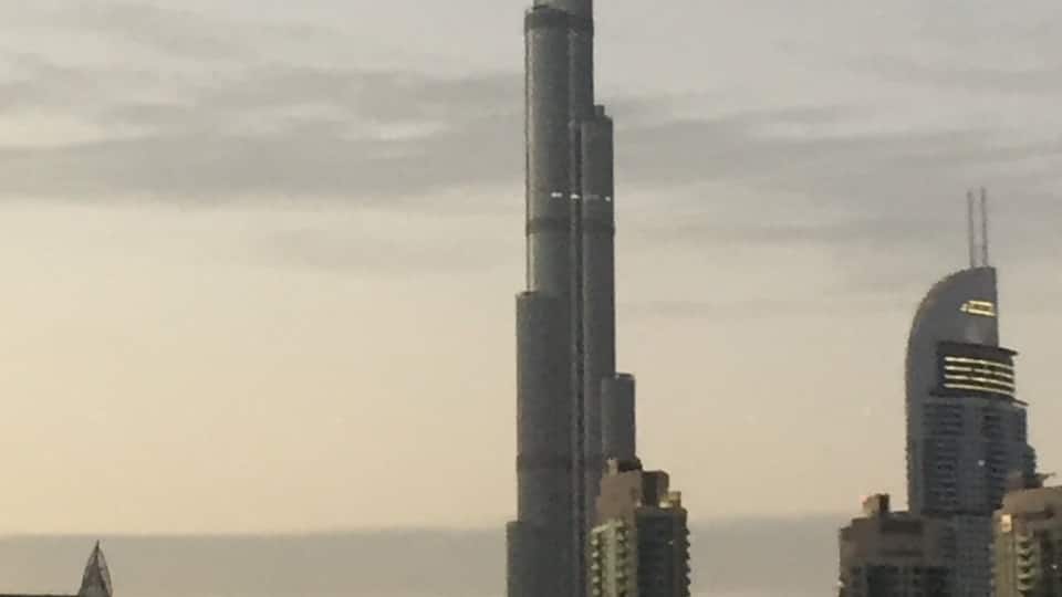 A cityscape with a prominent skyscraper, likely the Burj Khalifa, and other high-rise buildings.